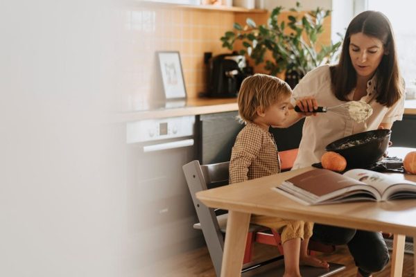 A mom and her child baking in a cozy kitchen surrounded by pumpkins.