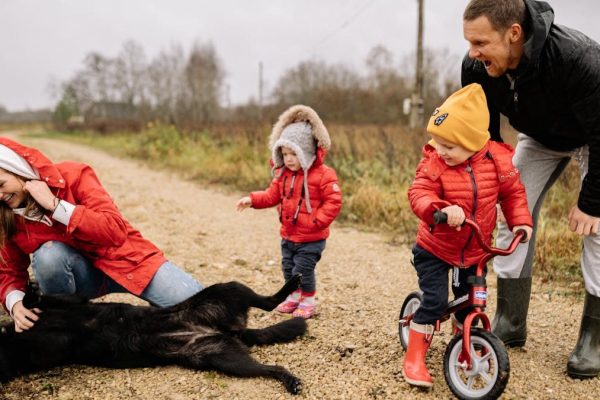 Happy family enjoying quality time outdoors with kids and dog in countryside.