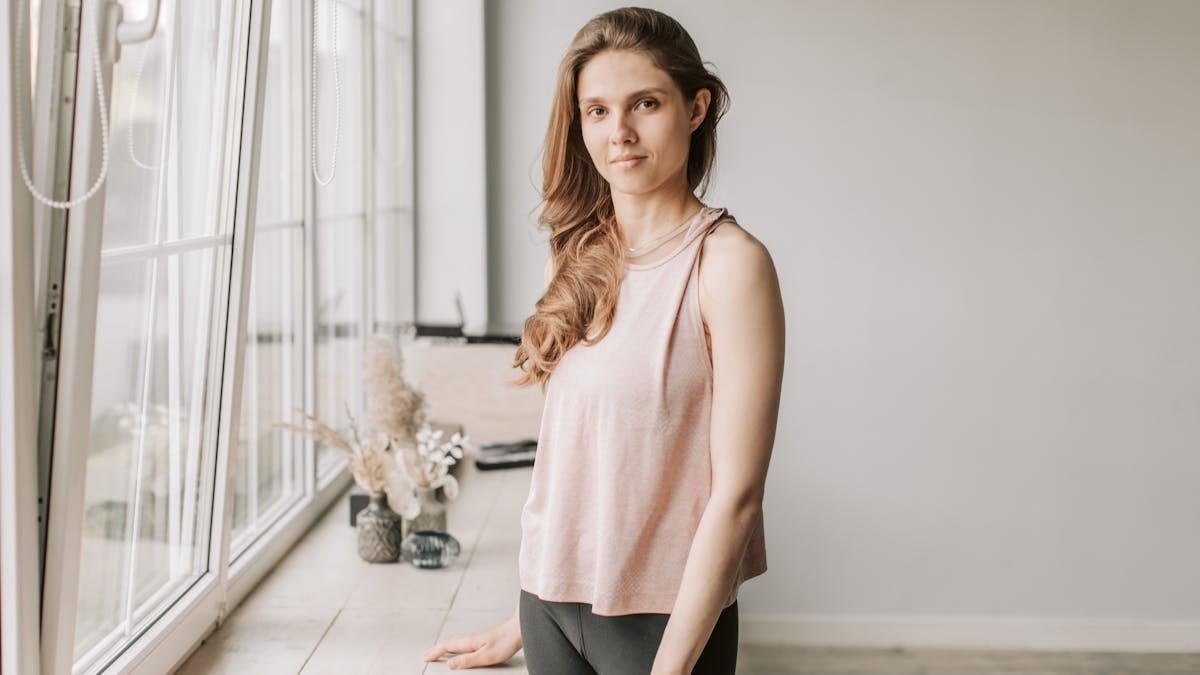 A young woman stands next to a sunlit windowsill, creating a tranquil ambiance.